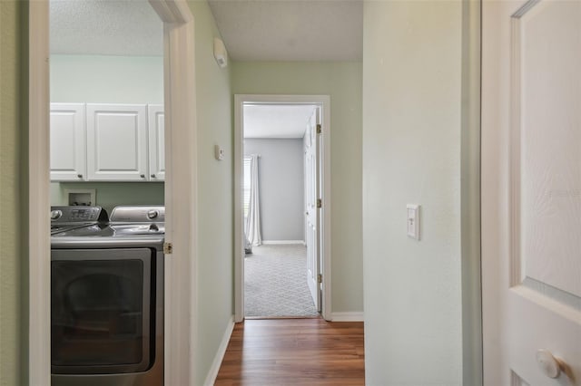 clothes washing area featuring a textured ceiling, cabinets, dark wood-type flooring, and washing machine and dryer