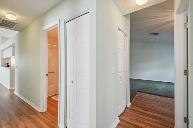 hallway with hardwood / wood-style floors and a textured ceiling