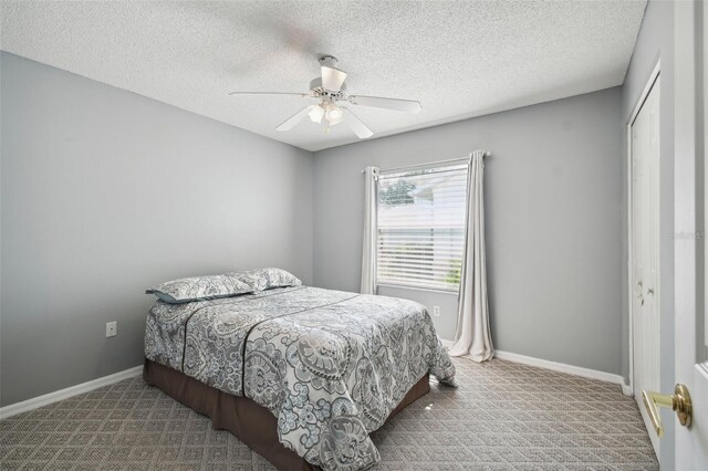 carpeted bedroom with ceiling fan, a textured ceiling, and a closet