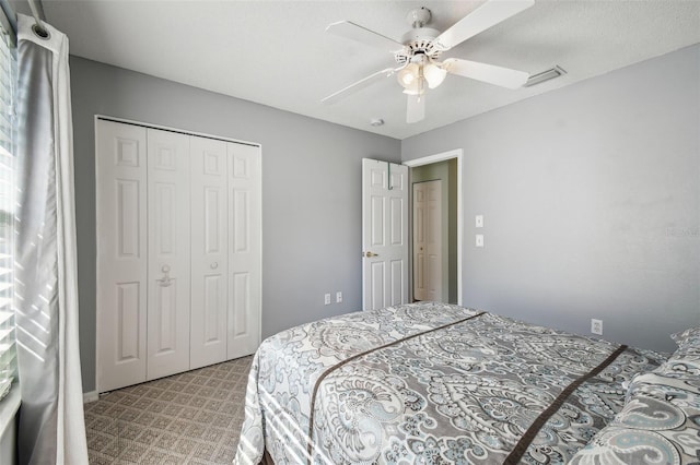 carpeted bedroom with ceiling fan, a closet, and a textured ceiling