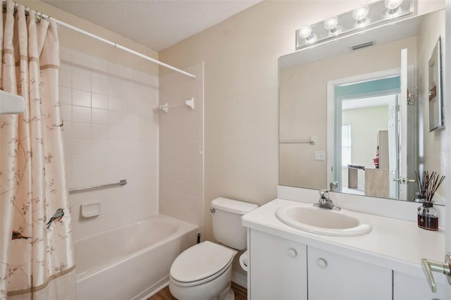 full bathroom with hardwood / wood-style floors, a textured ceiling, toilet, vanity, and shower / tub combo