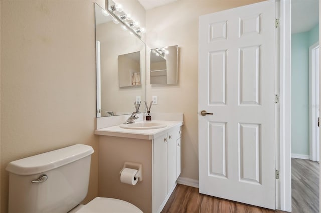 bathroom featuring toilet, vanity, and hardwood / wood-style flooring