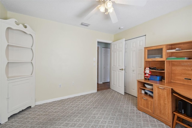 carpeted office space with ceiling fan