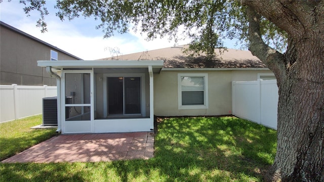 rear view of property featuring a lawn, a sunroom, and cooling unit