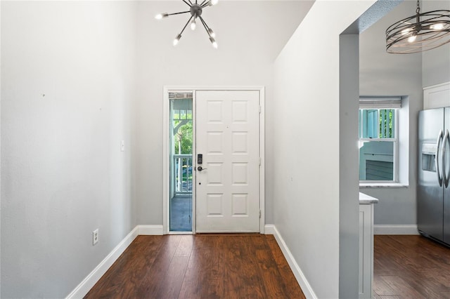 entryway with an inviting chandelier and dark wood-type flooring