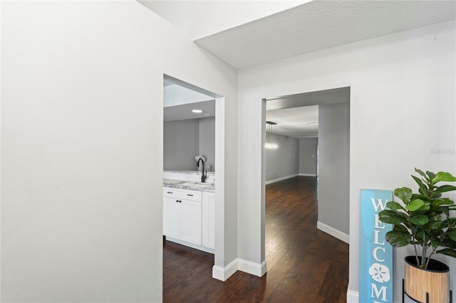 corridor with sink, dark wood-type flooring, and a textured ceiling