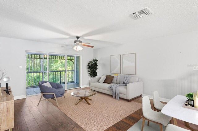 living room featuring a textured ceiling, dark hardwood / wood-style flooring, and ceiling fan