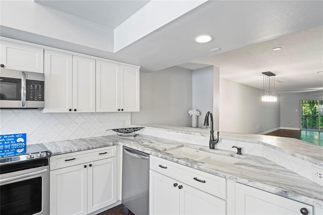 kitchen featuring white cabinetry, sink, kitchen peninsula, pendant lighting, and appliances with stainless steel finishes