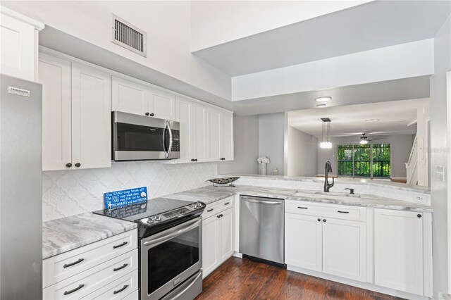 kitchen featuring kitchen peninsula, appliances with stainless steel finishes, sink, dark hardwood / wood-style floors, and white cabinetry