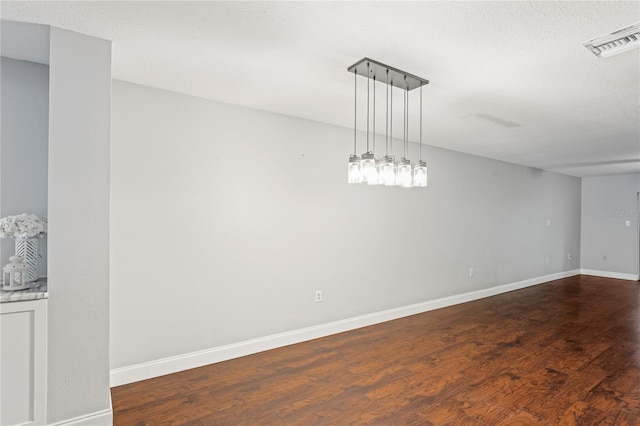 unfurnished room featuring dark wood-type flooring and a textured ceiling