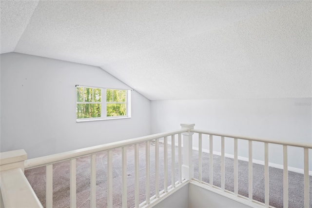 hall featuring carpet flooring, a textured ceiling, and vaulted ceiling