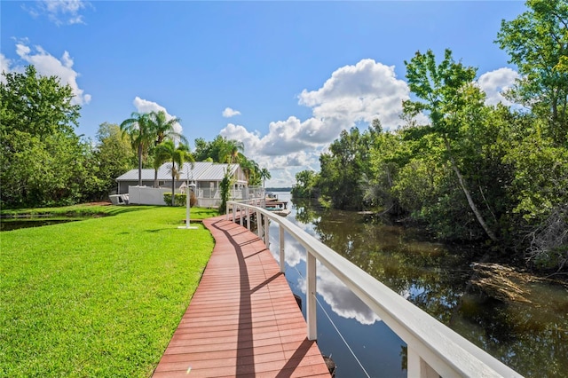 view of dock featuring a water view and a yard