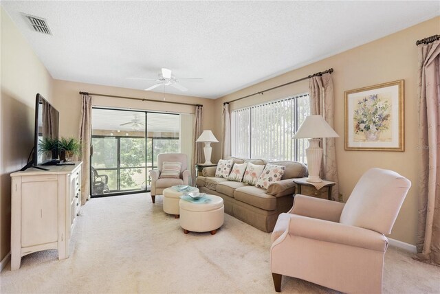 carpeted living room with a wealth of natural light, ceiling fan, and a textured ceiling