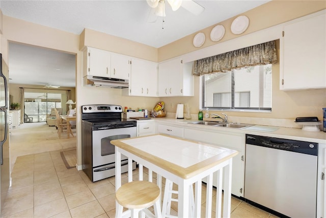 kitchen with sink, light tile patterned floors, ceiling fan, stainless steel appliances, and white cabinets