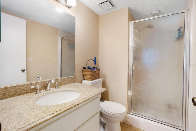 bathroom featuring tile patterned flooring, vanity, a textured ceiling, toilet, and walk in shower