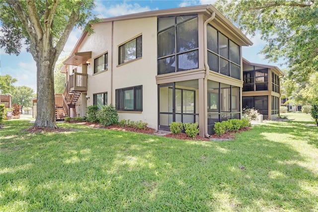 rear view of property with a sunroom and a lawn