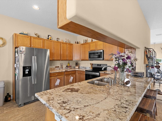 kitchen with light stone countertops, sink, a kitchen breakfast bar, a textured ceiling, and appliances with stainless steel finishes