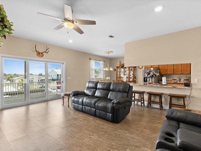 living room with ceiling fan with notable chandelier