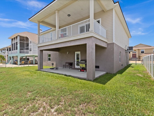 back of house featuring a lawn, a sunroom, a balcony, and a patio