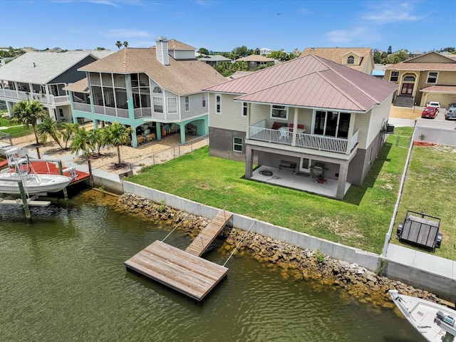 back of property with a lawn, a sunroom, a water view, and a patio