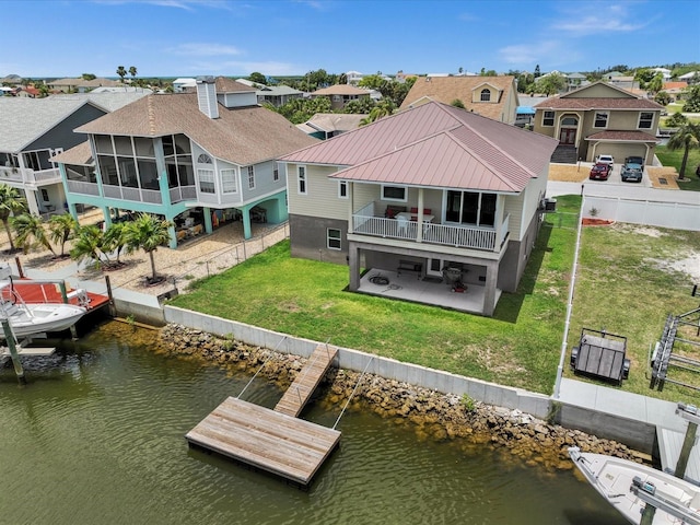 back of house featuring a balcony, a water view, a sunroom, a patio, and a lawn