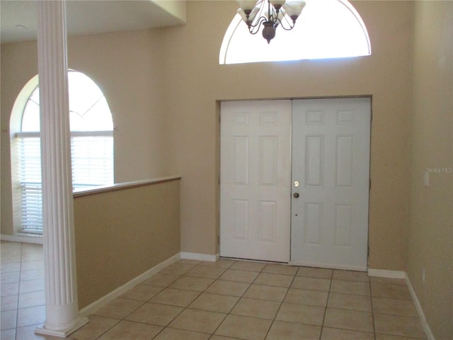 foyer entrance featuring an inviting chandelier, light tile patterned floors, and ornate columns