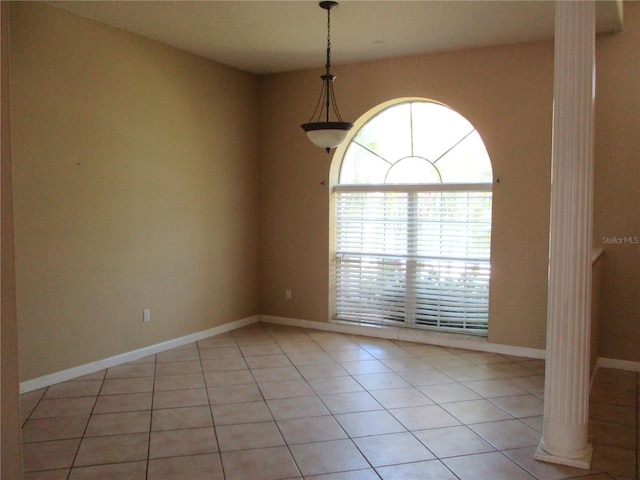 empty room featuring decorative columns and light tile patterned flooring