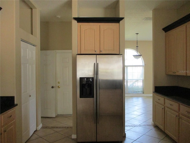 kitchen with stainless steel refrigerator with ice dispenser, light tile patterned flooring, light brown cabinetry, and decorative light fixtures