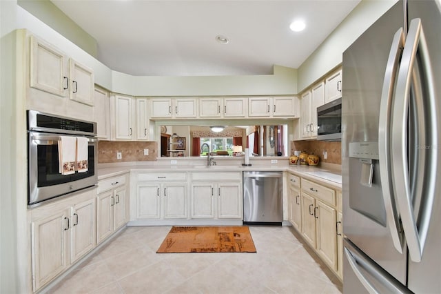 kitchen with backsplash, appliances with stainless steel finishes, sink, and light tile floors