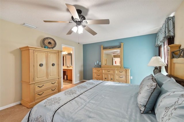 bedroom with a textured ceiling, ceiling fan, light colored carpet, and ensuite bath