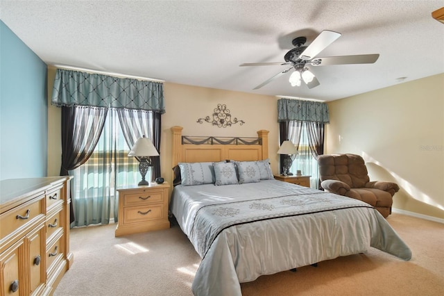 bedroom featuring light colored carpet, ceiling fan, and a textured ceiling