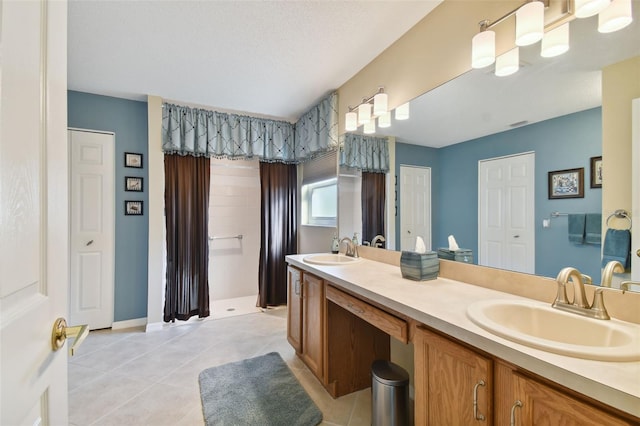 bathroom with dual bowl vanity, tile flooring, and a textured ceiling