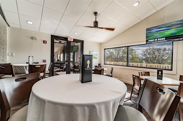 dining room featuring ceiling fan, a drop ceiling, lofted ceiling, and brick wall