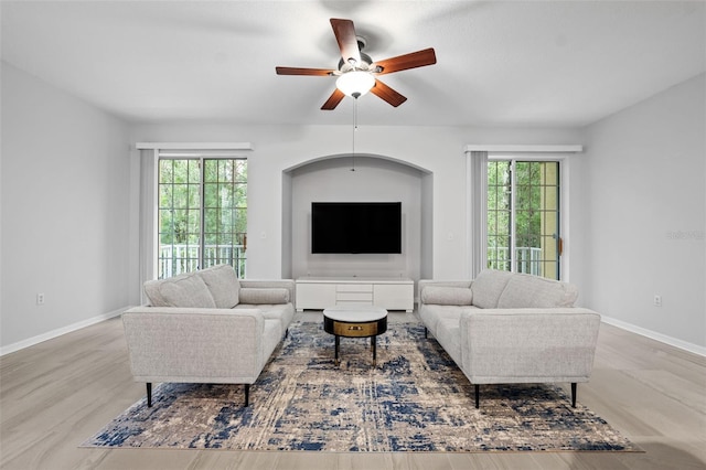 living room with a wealth of natural light, ceiling fan, and light hardwood / wood-style flooring