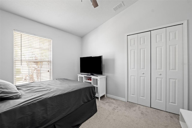 bedroom with ceiling fan, a closet, light colored carpet, and vaulted ceiling