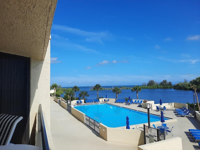 view of swimming pool with a water view and a patio