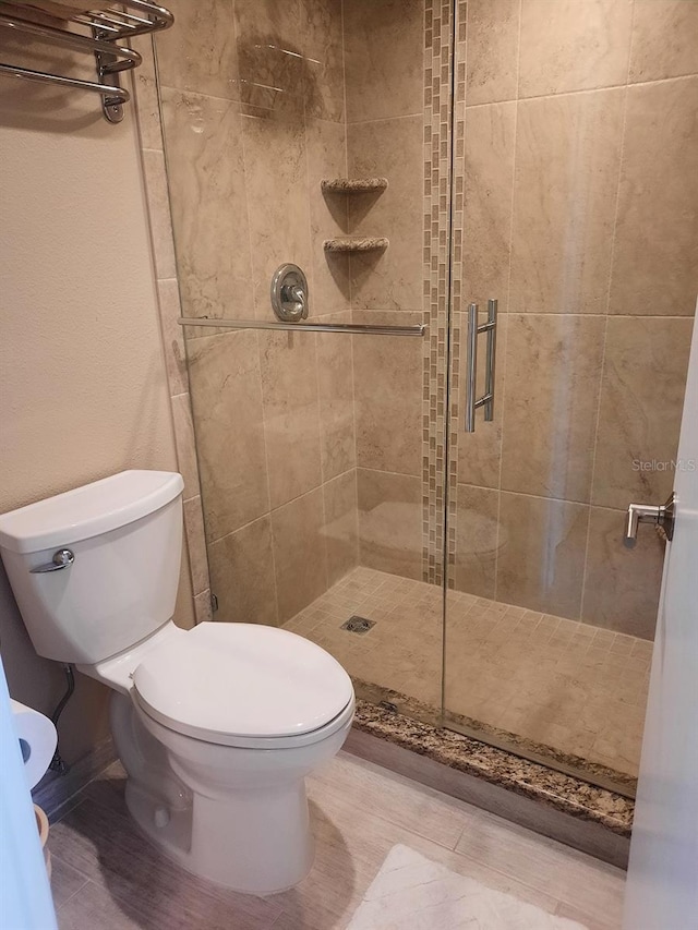 bathroom with toilet and a shower with shower door