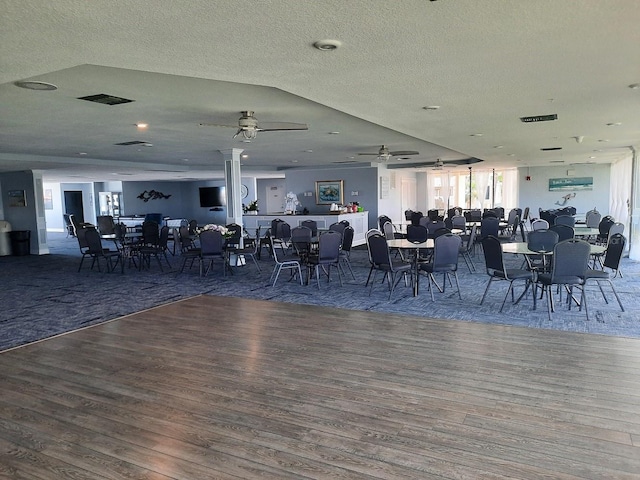 unfurnished dining area with ceiling fan, dark hardwood / wood-style flooring, and a textured ceiling