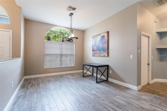 dining space featuring a textured ceiling and light hardwood / wood-style floors