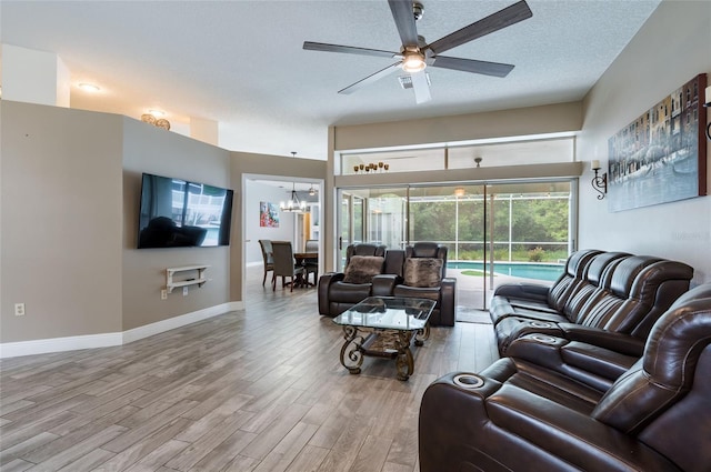 living room with hardwood / wood-style floors, ceiling fan with notable chandelier, and a textured ceiling