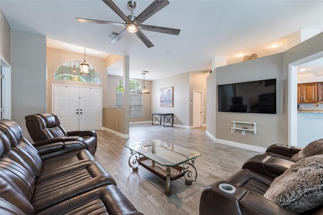 living room featuring ceiling fan with notable chandelier and light wood-type flooring