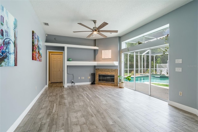 unfurnished living room featuring ceiling fan, hardwood / wood-style floors, and a textured ceiling