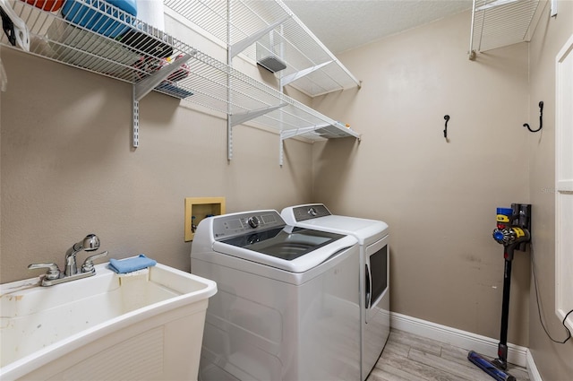 washroom featuring washer and dryer, light wood-type flooring, and sink