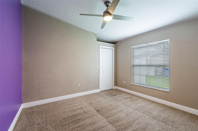 carpeted empty room featuring a textured ceiling, vaulted ceiling, and ceiling fan