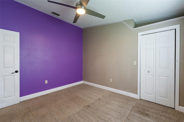 unfurnished bedroom with ceiling fan, a textured ceiling, a closet, carpet, and ornamental molding