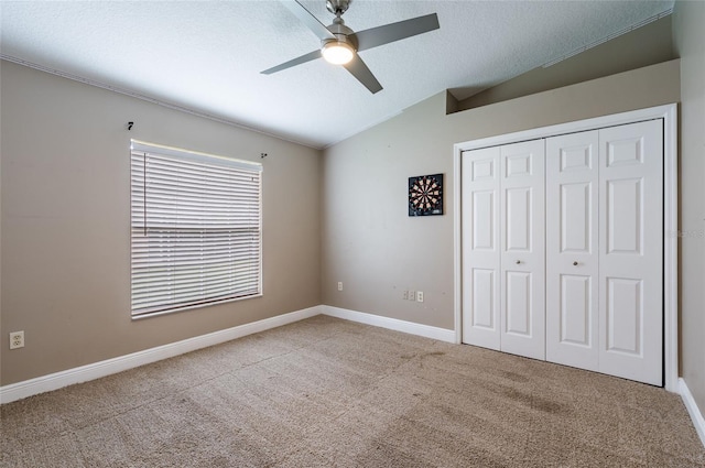 unfurnished bedroom with ceiling fan, a closet, light colored carpet, and vaulted ceiling