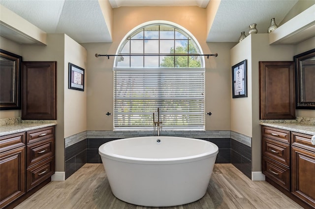 bathroom with vanity, tile walls, and a tub