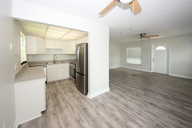 kitchen featuring white cabinetry, sink, light hardwood / wood-style flooring, a textured ceiling, and appliances with stainless steel finishes