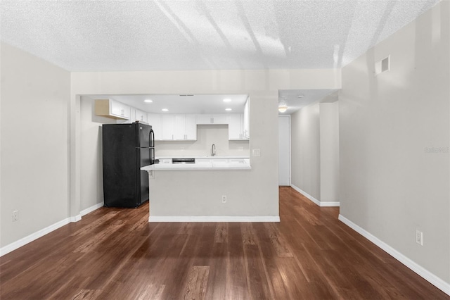 kitchen featuring a textured ceiling, black fridge, white cabinets, and dark hardwood / wood-style floors