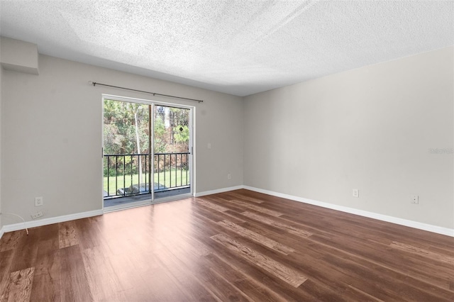 spare room featuring dark hardwood / wood-style floors and a textured ceiling